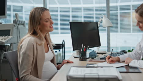 gynecologist listening pregnant woman in medical office. closeup doctor writing