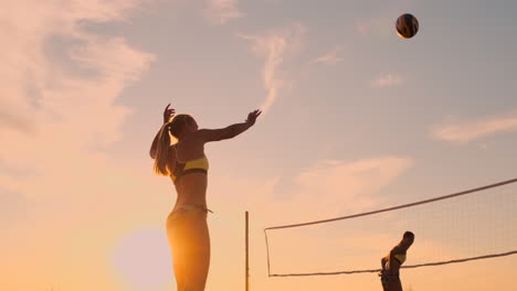 Servicio-De-Voleibol-De-Playa:-Mujer-Sirviendo-En-Un-Juego-De-Voleibol-De-Playa.-Saque-Con-Remate-Por-Encima-De-La-Cabeza.-Jóvenes-Divirtiéndose-Bajo-El-Sol-Viviendo-Un-Estilo-De-Vida-Deportivo-Activo-Y-Saludable-Al-Aire-Libre