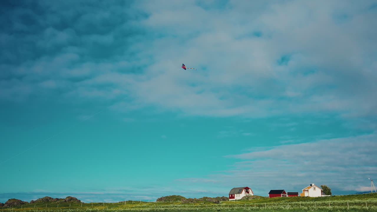 Picturesque nordic landscape. Bright blue sky, vibrant green grass. A kite flying in the sky. Norwegian landmark in summertime.