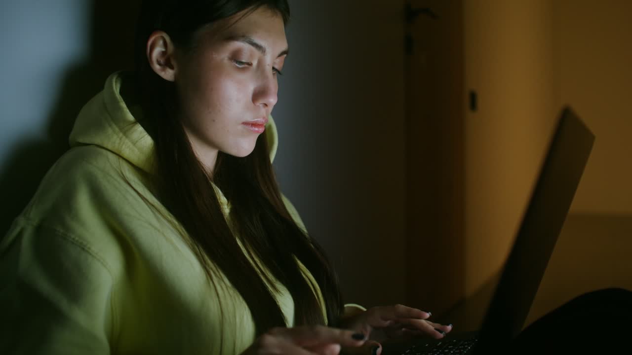 Giovane donna che lavora al portatile di notte