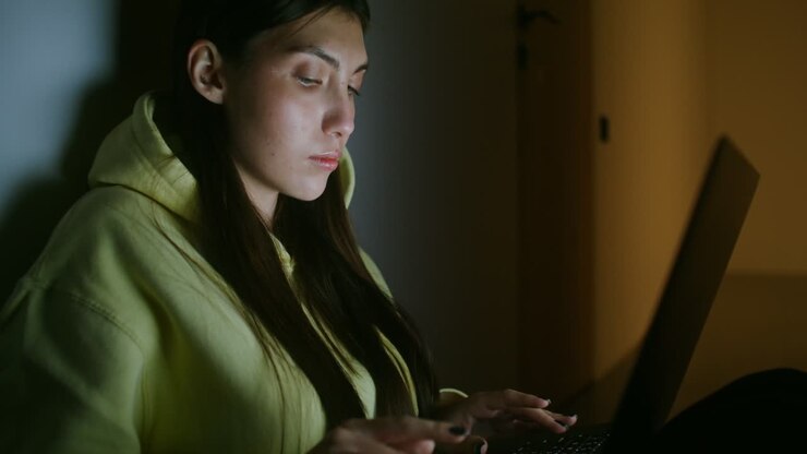 Giovane donna che lavora al portatile di notte