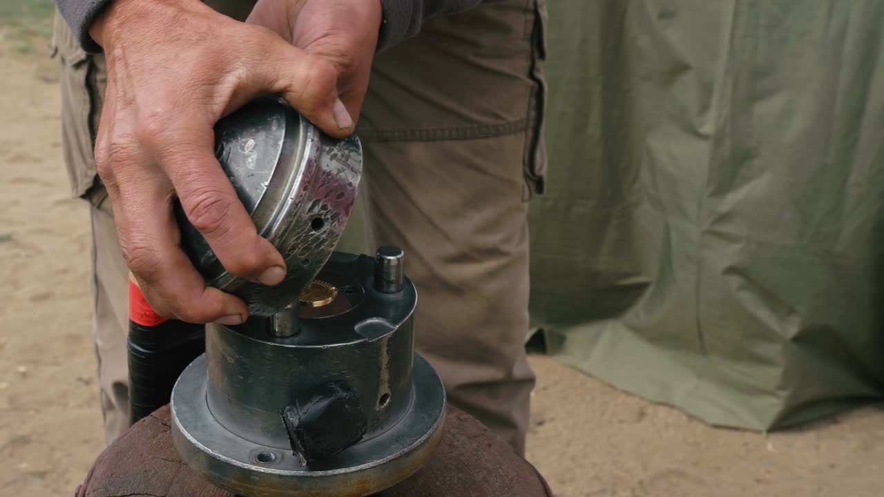 사람들은 텐트 근처에 도구와 망치로 기념품 동전을 만니다.