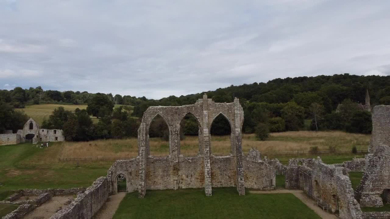 Rising aerial view through the arches of Old Bayham Abbey, Kent. Historic medieval ruins framed by lush countryside, perfect for travel, heritage, or cinematic projects