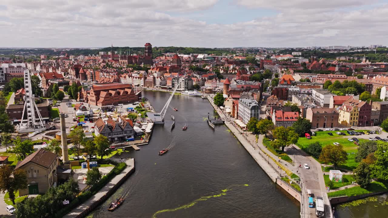 Establishing aerial of Gdansk Old Town waterfront with river boats and skyline
