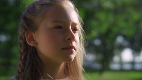 thoughtful pretty girl looking in distance in city park closeup. golden sunlight