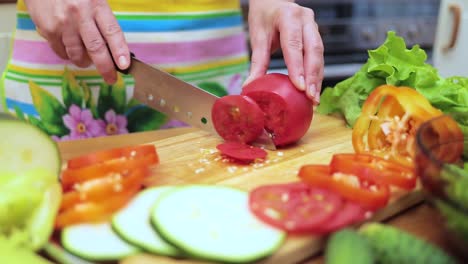 women's hands housewives cut with a knife fresh tomato on the cutting board of the kitchen table