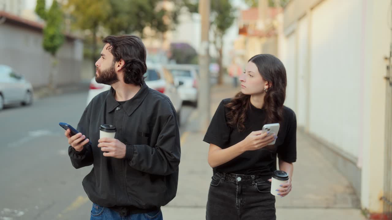 People on a city street using smartphones and holding coffee cups