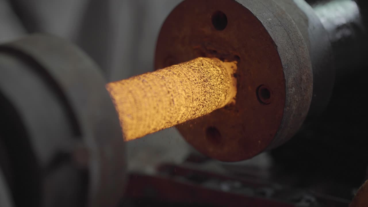 Primo piano della forgiatura del metallo, produzione di acciaio incandescente su un tornio