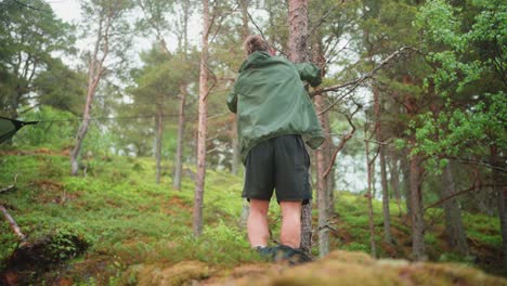 caucasian guy setting up hammock camping shelter in forest