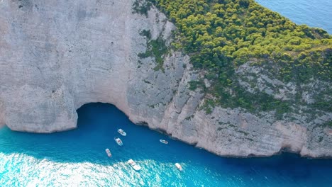 yates turísticos y barcos estacionados en aguas azules profundas a lo largo de los enormes acantilados de la isla de zakynthos, grecia
