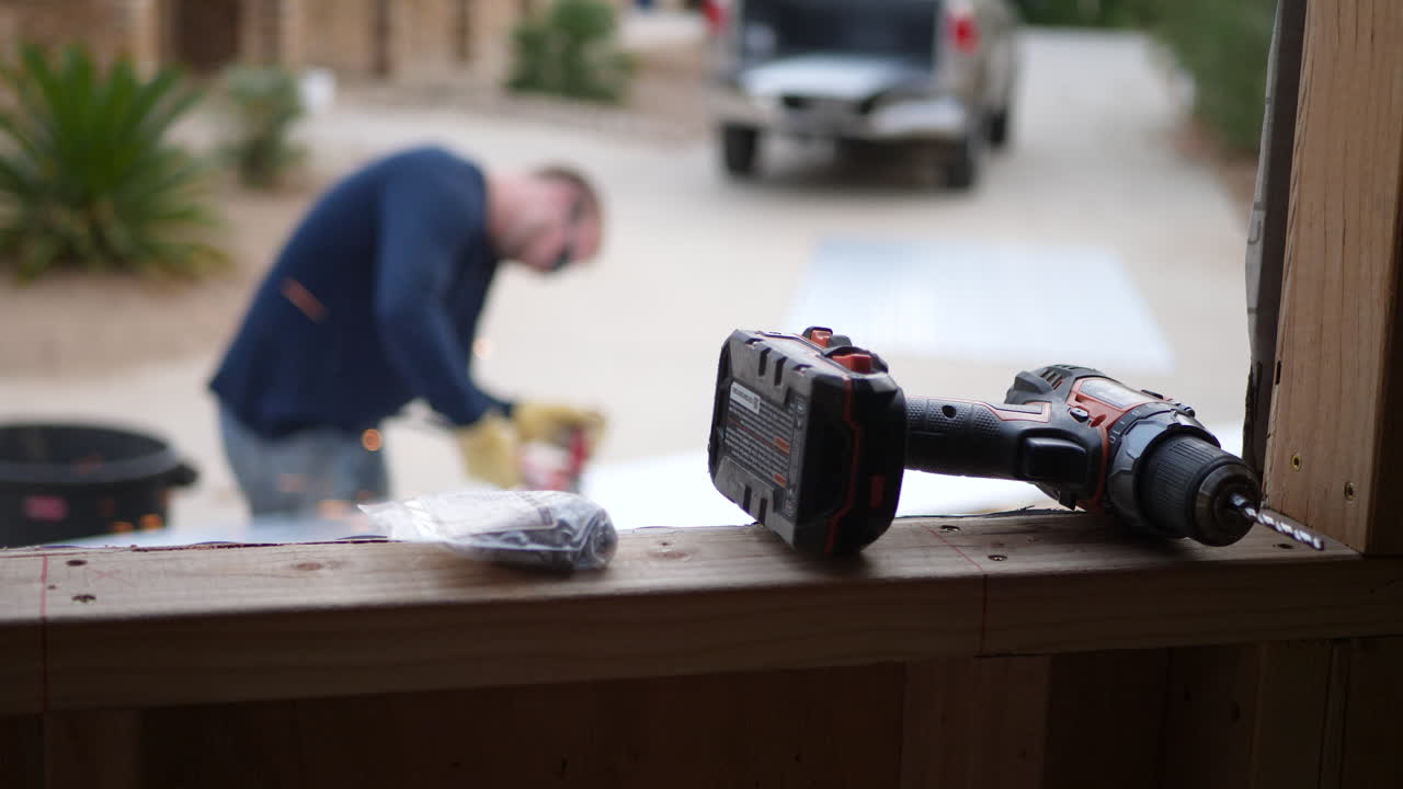 A male construction worker using a power tool angle grinder to cut metal with sparks flying on the job site