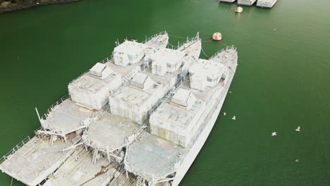 Upward-Dolly-Aerial-View-of-Three-Large-Derelict-Ships-in-Body-of-Water