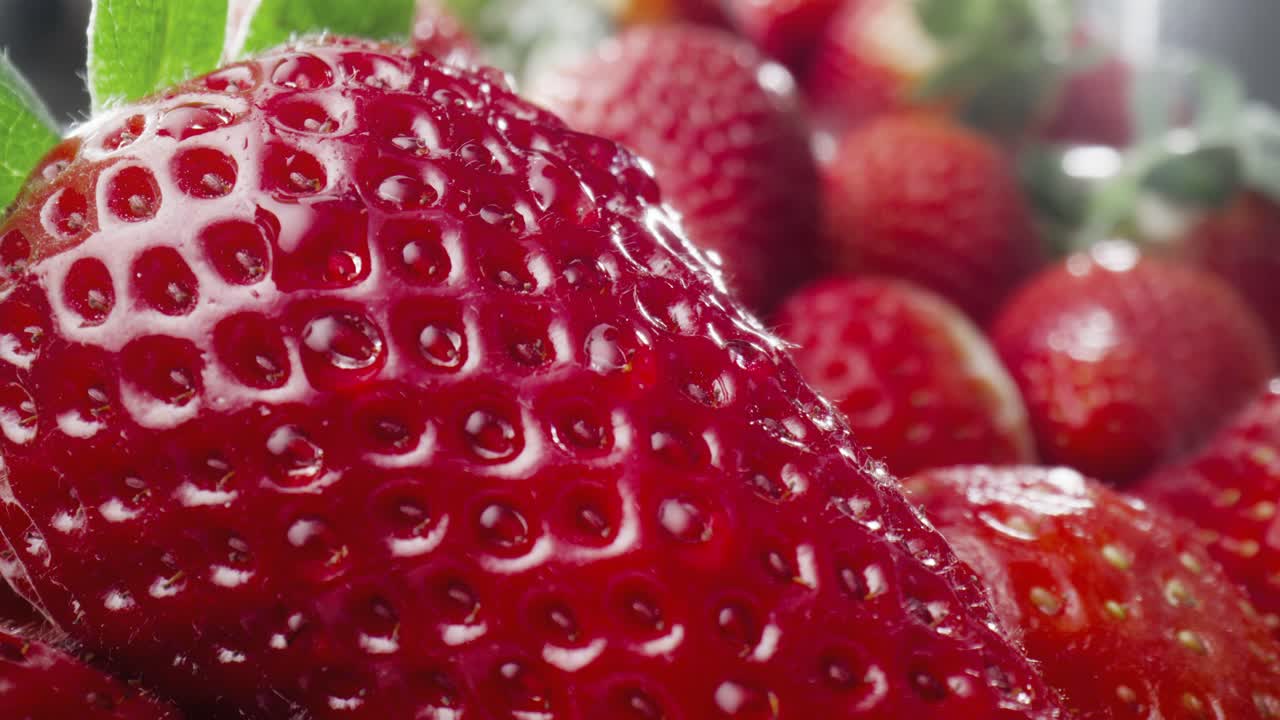 Macro video of water drop falling off the strawberry