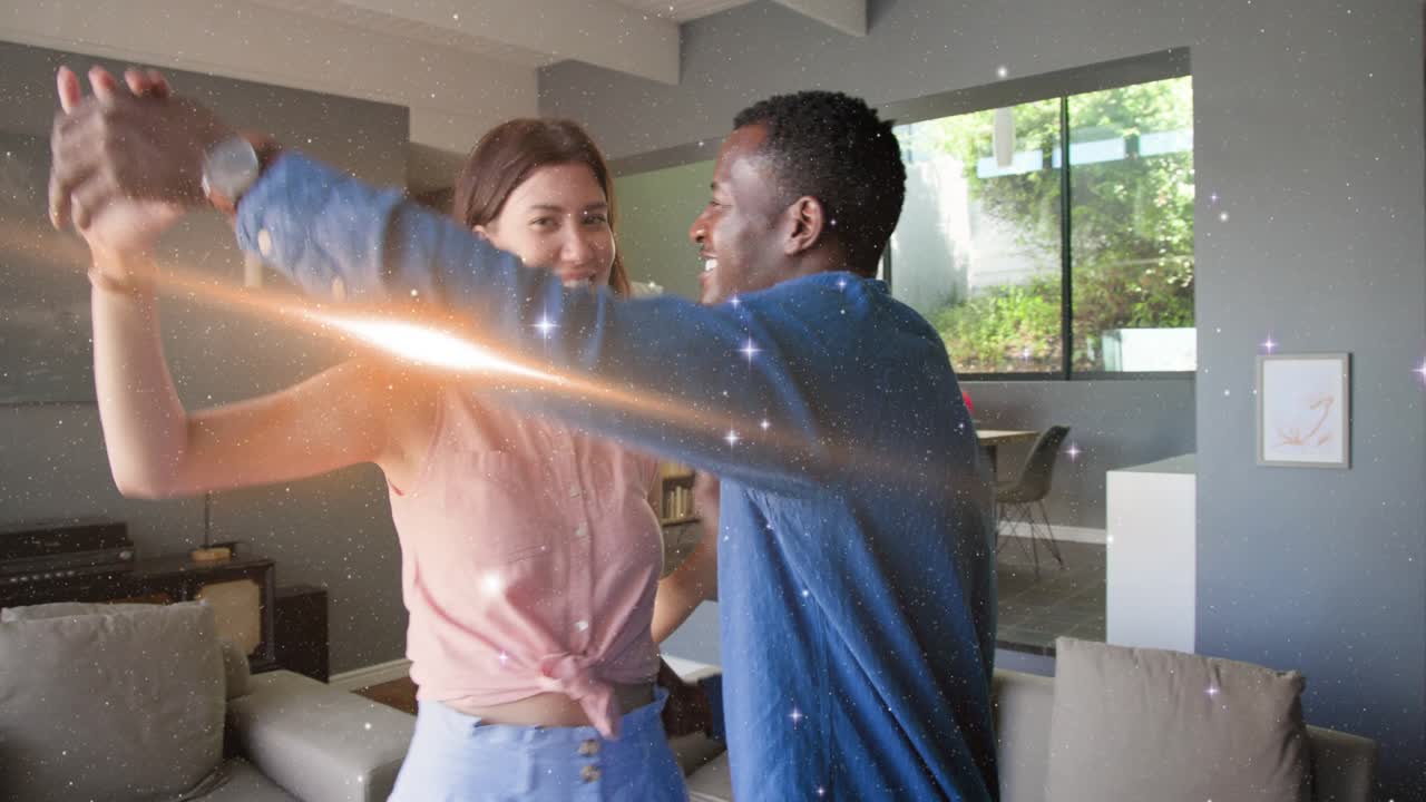 Couple smiling and leaning in, guiding turn in living room, sparkles adding romance for marketing
