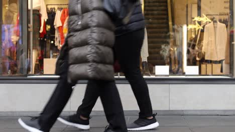 close up on feet as shoppers walk past a high end store