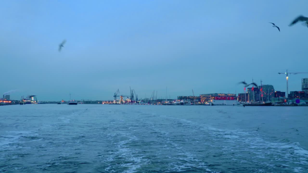 암스테르담의 산업 항구, 건설 크레인과 현대적인 해안 건물, 부드러운 파란색 저녁 빛과 물은 조용하지만 활기찬 도시 풍경을 만니다.