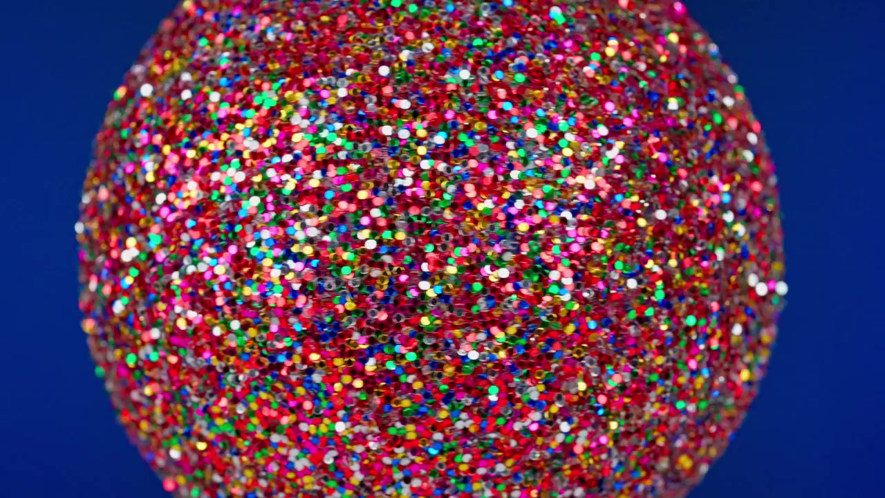 Sfera glitterata colorata rotante su sfondo blu