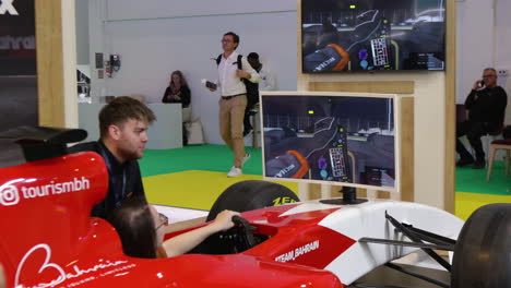 a young girl playing f1 simulator in a world travel market exhibition in london.
