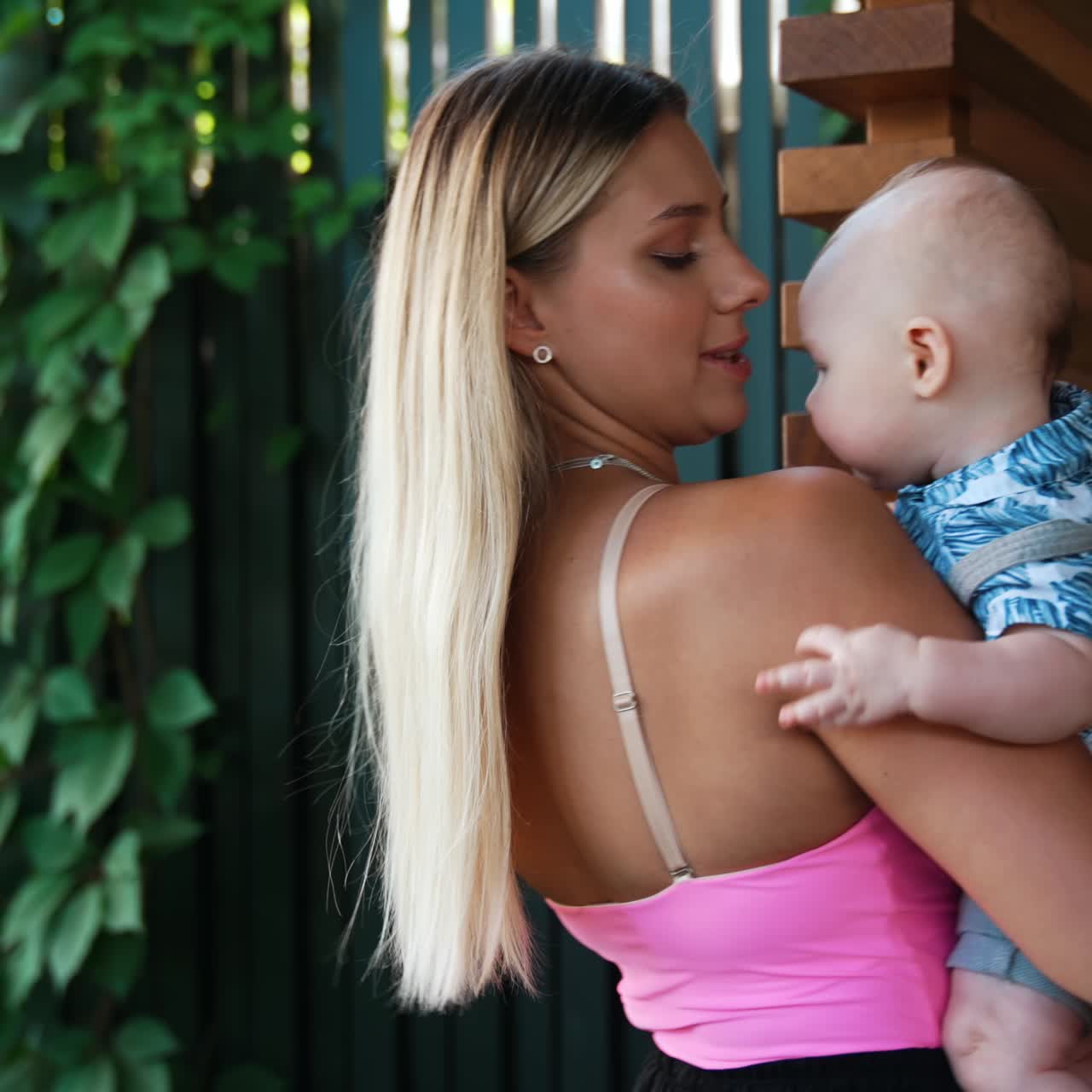 Linda mulher loira segurando um bebê nos braços. Mãe com seu filho pequeno ao ar livre no verão