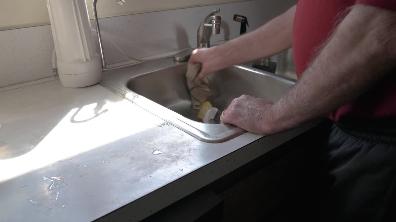 Homem limpando e secando uma pia na cozinha - Close-up.