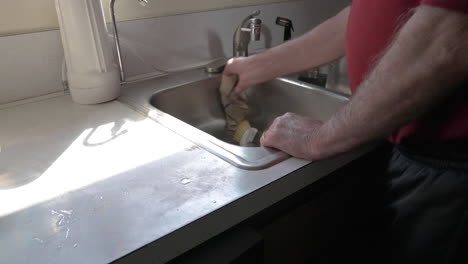 man cleaning and wiping a sink in the kitchen - closeup shot