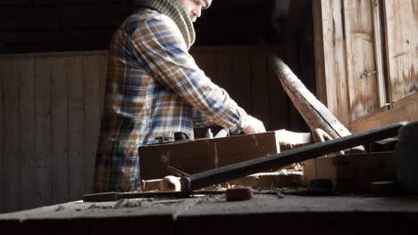 Man-uses-tools-to-work-on-parts-in-workshop-with-natural-light-from-window