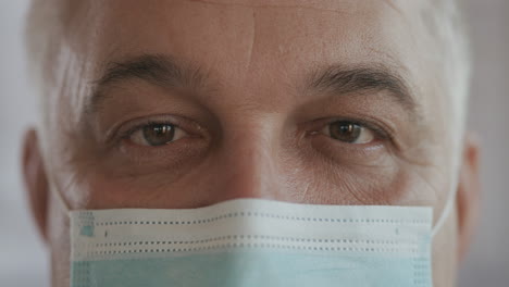 un hombre mayor con una máscara de protección mira a la cámara. estrecho extremo de los ojos y la cara en una máscara protectora. imágenes de alta calidad 4k