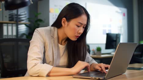 a young woman in business attire concentrates on her laptop in a contemporary office environment filled with plants and natural light, suggesting a busy afternoon filled with important tasks.