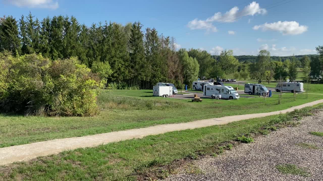 un aire en francia con autocaravanas estacionadas junto a un lago artificial en un buen día