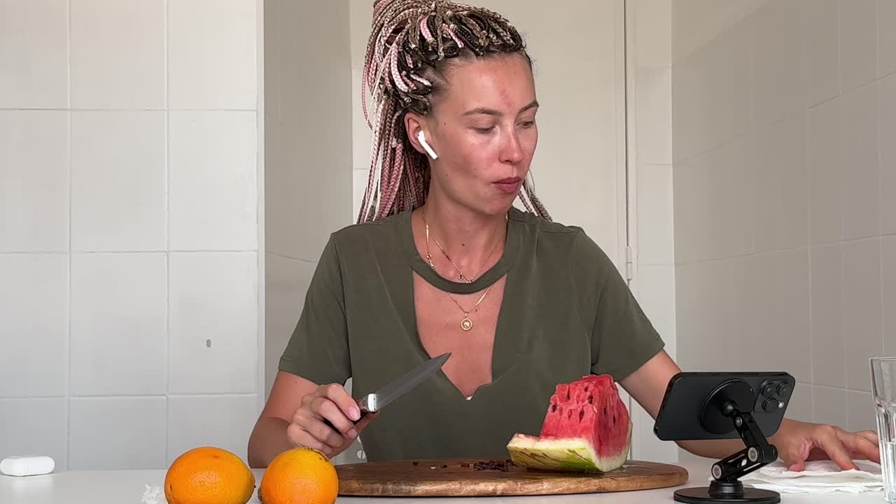 Mladá žena krájí a jí čerstvý meloun.
