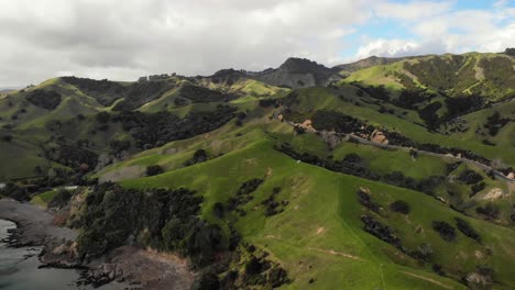 Aerial-View-of-mountains-and-grassy-hills-in-Coromandel-peninsula-New-Zealand,-pullback