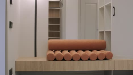 un interior de casa moderno con una innovadora almohada cilíndrica en un armario de madera, iluminación ambiental y soluciones de almacenamiento elegantes
