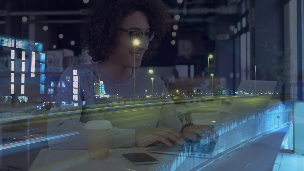 Animation of smiling woman using laptop in cafe, over sped up traffic in city at night