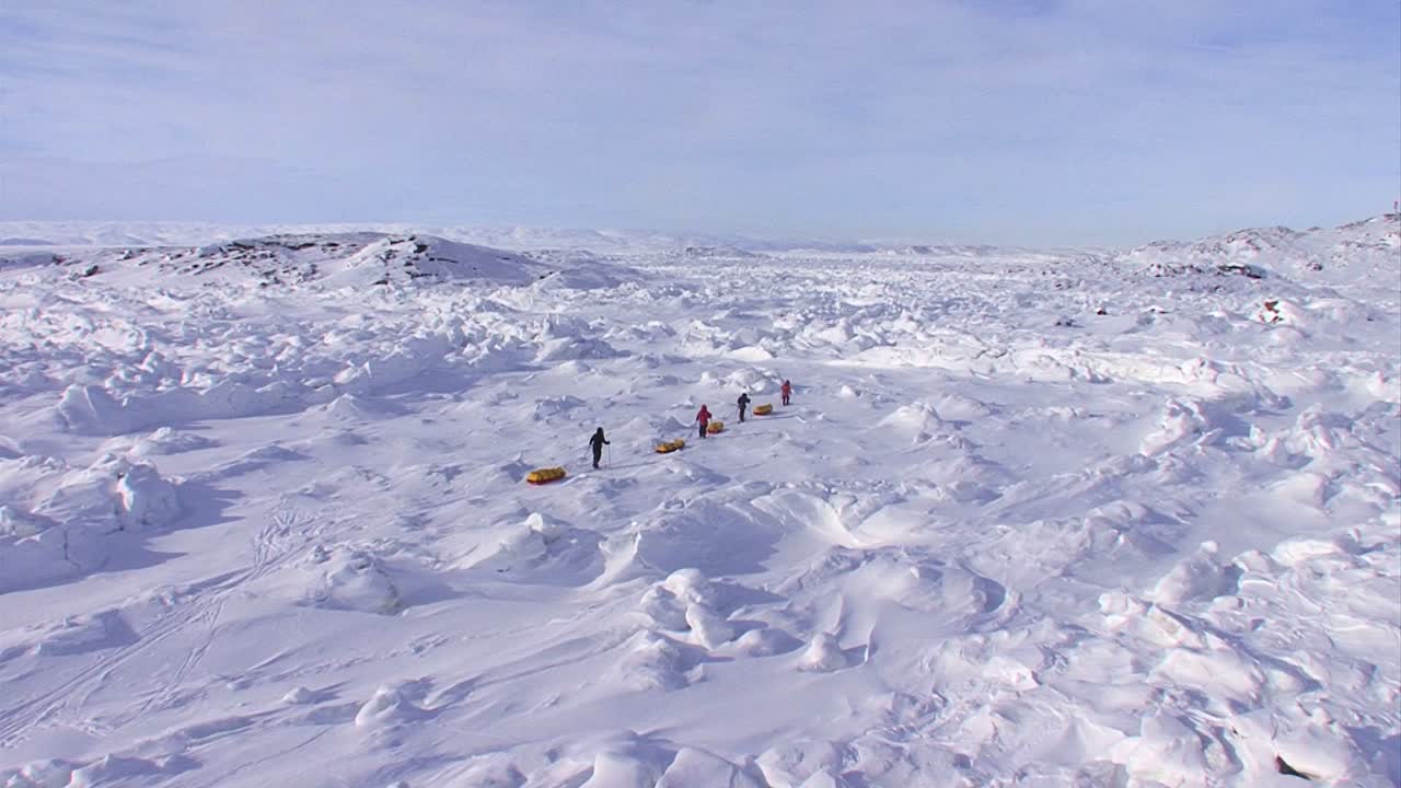 An Arctic expedition moves across a vast landscape of frozen tundra on cross country skis towing supplies