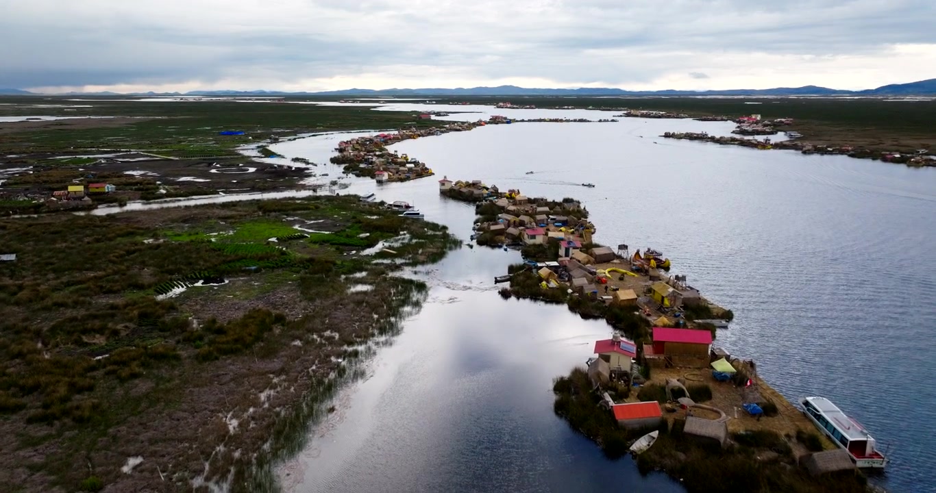 Dronen dolly-kuva Urosin kelluvista saarista Titicaca-järvellä lähellä Punon kaupunkia, Perussa, ilmakuva telttojen ja kotien taustasta.