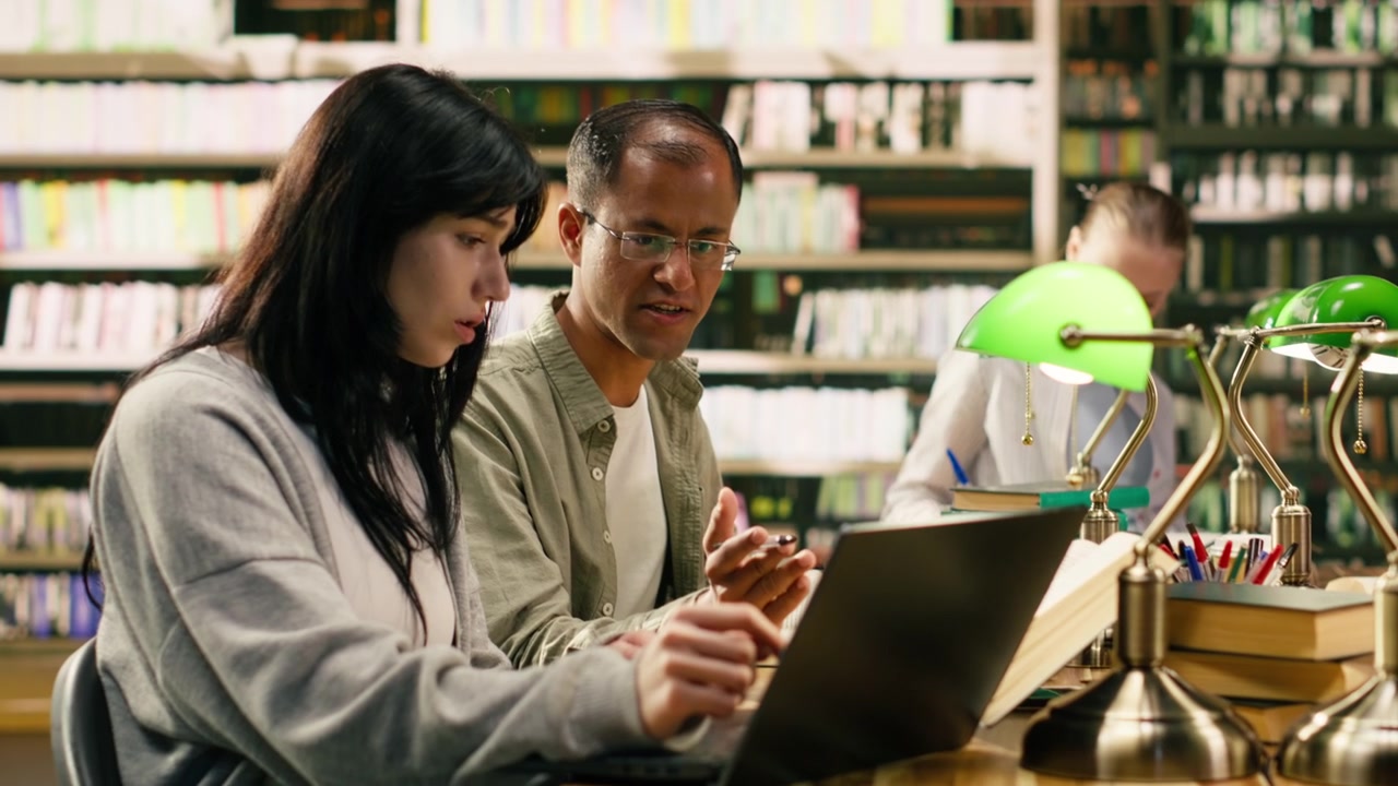 Veileder peker mot laptop og forklarer pensum til studenten