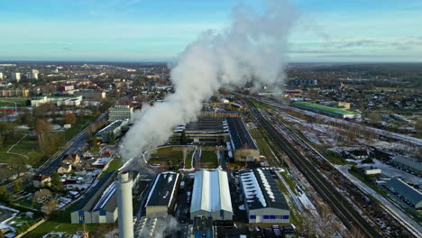 factory emits smoke over small township, aerial drone view