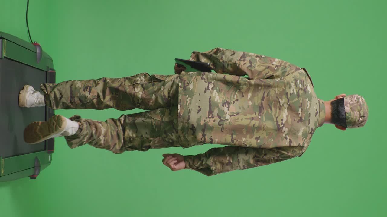녹색 스크린 배경 스튜디오에서 는 동안 태블릿을 들고 있는 아시아 남성 군인