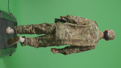 cuerpo lleno de vista trasera hombre asiático soldado sosteniendo una tableta mientras caminaba en el estudio de fondo de la pantalla verde
