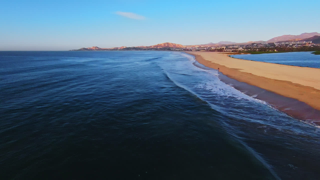 Cinematic aerial view sea surface of the cityscape of Cabo San Lucas, Mexico marina area at sunset, Los Cabos, Baja California Sur