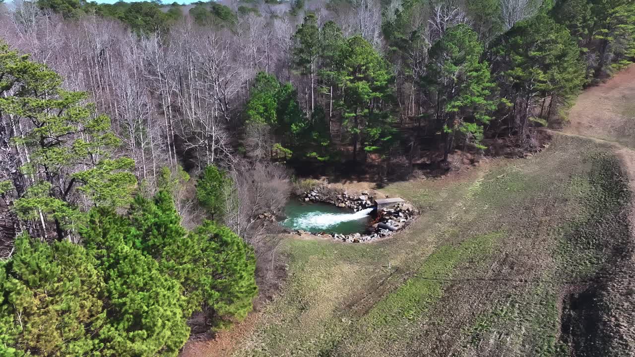 Discharging Water From A Pipe Into The Basin By The Forest. - aerial shot
