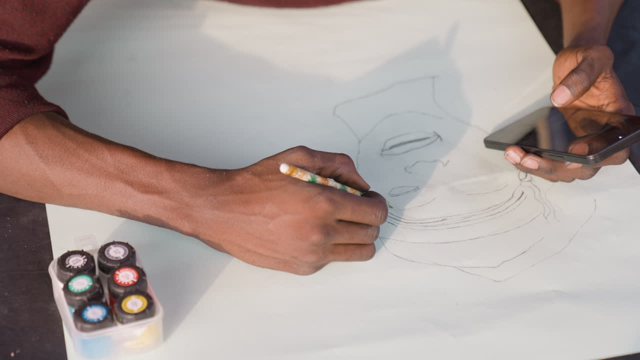 Black painter referencing phone while painting portrait on paper, translating dotted sketch into bold contours with watercolor and gouache. Warm workshop light, energetic hands, precise strokes