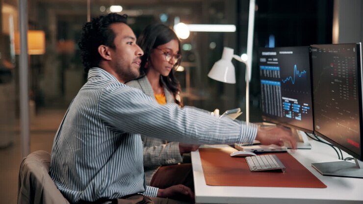Business Professionals Collaborating and Analyzing Data on Computer Screens in Office