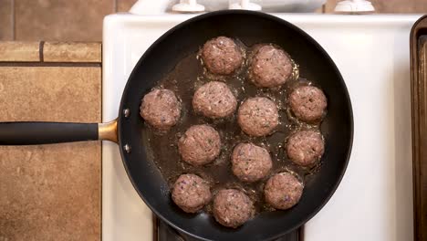 spiced lamb patties frying in a pan on the stove in hot olive oil - overhead view lamb patty series