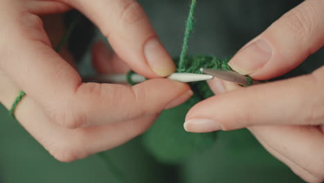 die hände einer nicht erkennbaren frau, die mit grüner wolle strickt 2