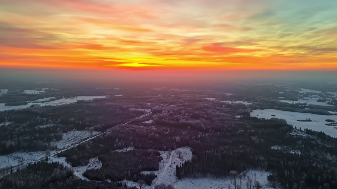 Panoramic aerial view of an orange sunrise over winter landscape