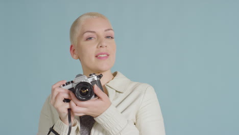 Female-caucasian-model-posing-with-vintage-SLR-against-blue-backdrop-03