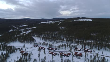 空中拍攝的飛行慢慢下降, 看到一個雪地風景, 房子被樹木包圍的森林在一個愉快的山谷