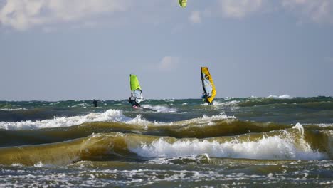 windsurfers surfing on high waves of baltic sea in poland