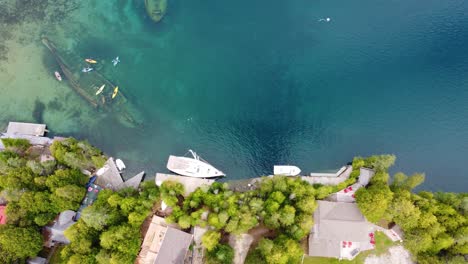 Beach-Houses-with-Sail-Boats-Docked-and-Kayaks-Floating-near-Sunken-Ships-in-Small-Canal-Connected-to-Georgian-Bay,-Ontario,-Canada